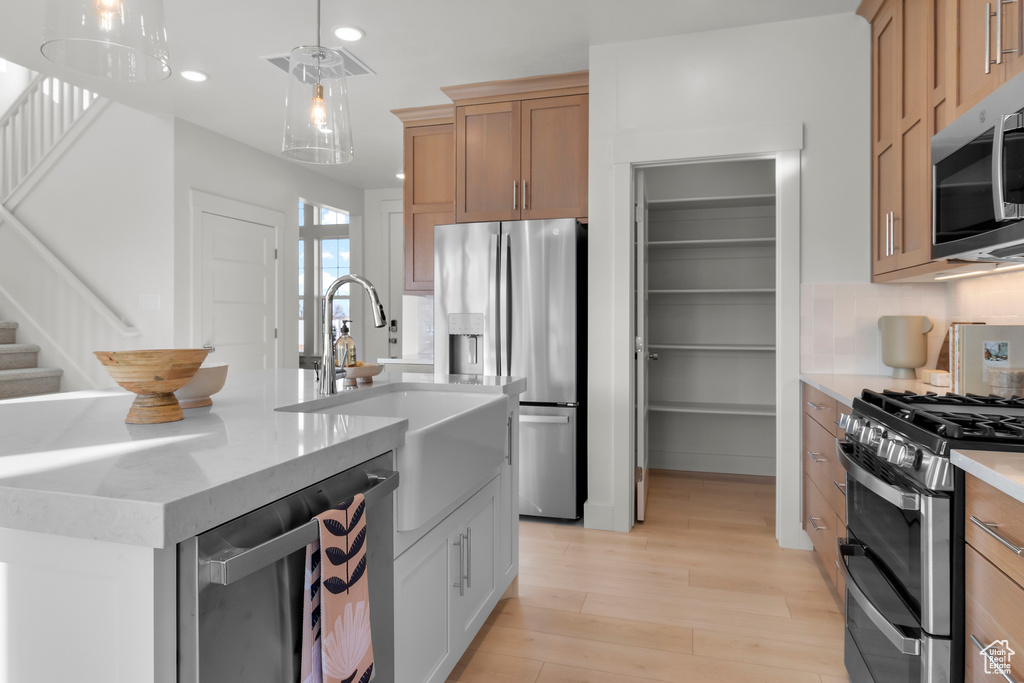 Kitchen featuring a sink, light wood-style floors, stainless steel appliances, decorative light fixtures, and recessed lighting