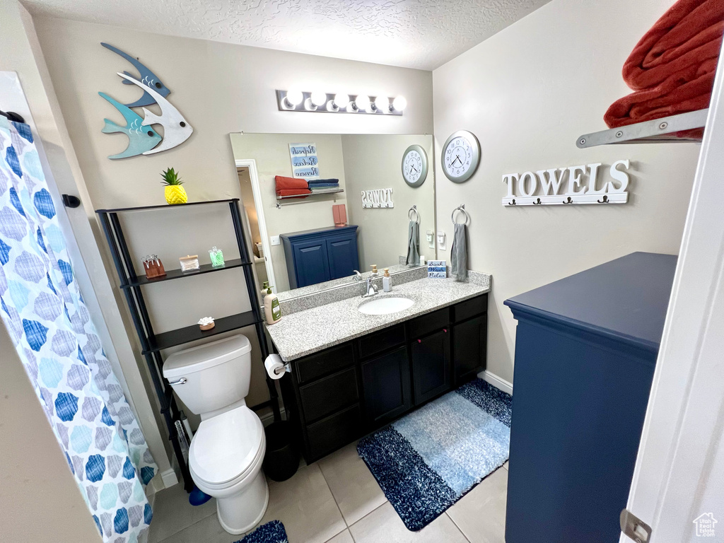 Full bathroom with vanity, tile patterned flooring, toilet, and a textured ceiling