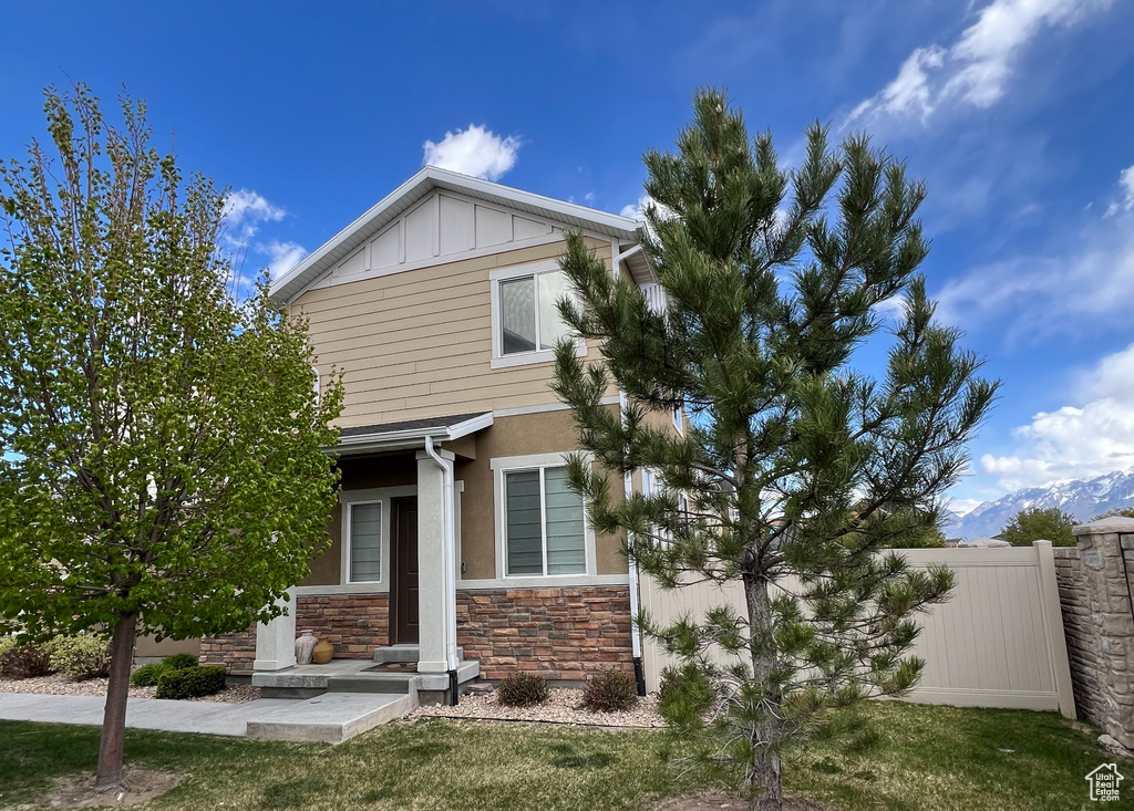 View of front of house featuring fence, board and batten siding, and stone siding