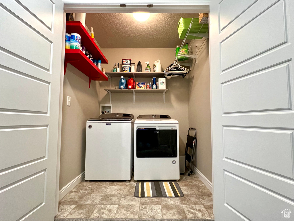 Laundry area featuring baseboards, a textured ceiling, and washing machine and dryer