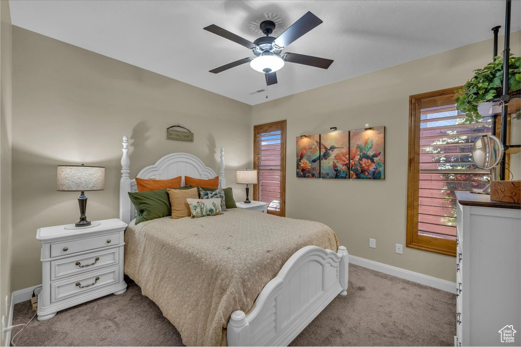 Bedroom with a ceiling fan, baseboards, and light carpet