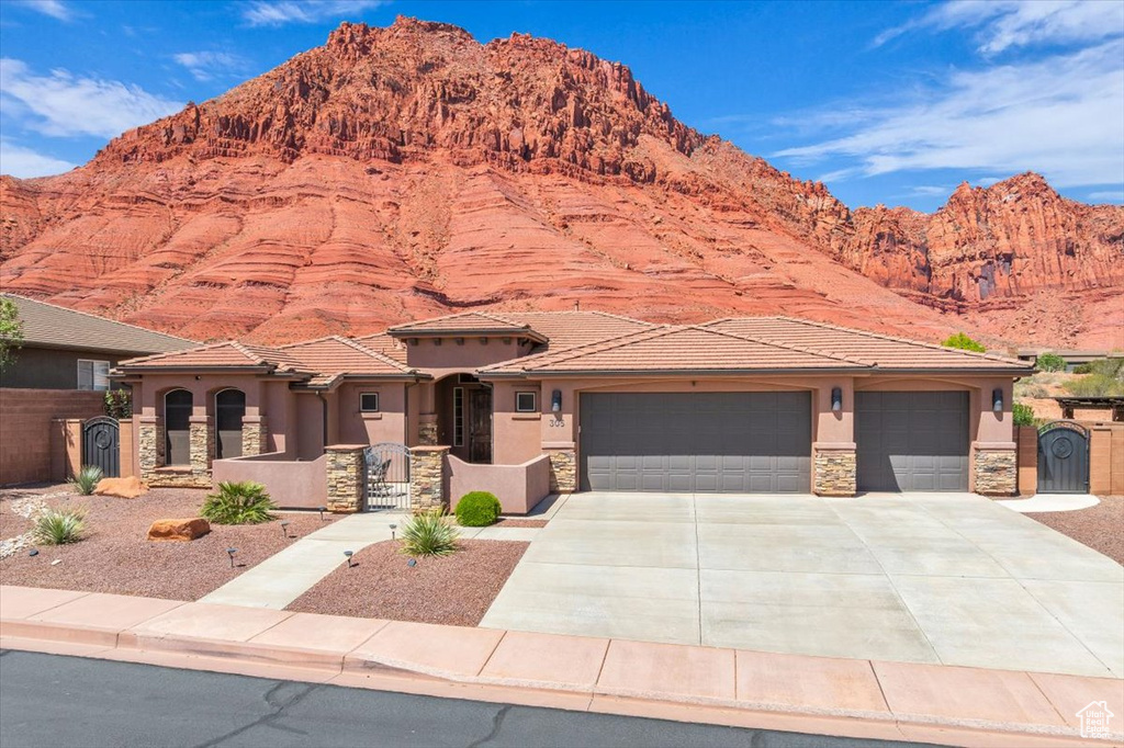 View of front of home featuring driveway, a garage, a mountain view, stone siding, and stucco siding
