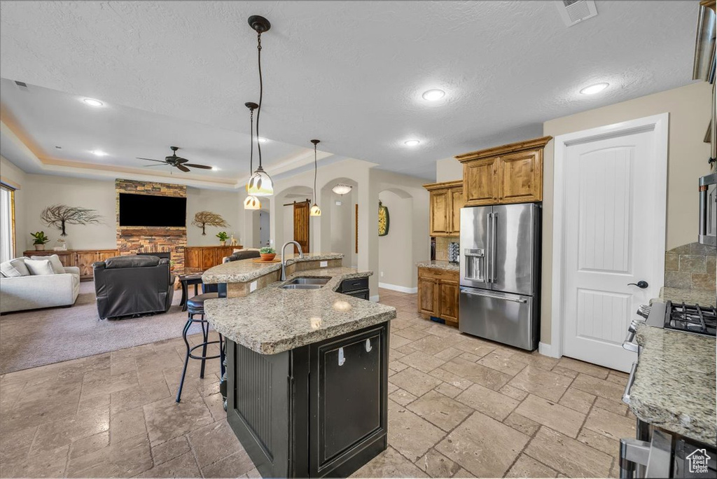 Kitchen with arched walkways, high quality fridge, a sink, stone tile flooring, and open floor plan
