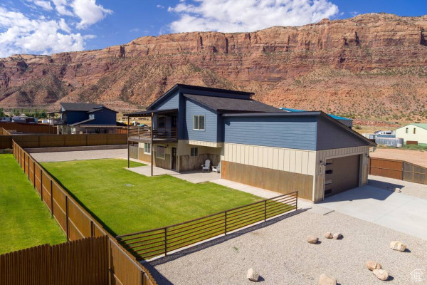 Exterior space with concrete driveway, a fenced backyard, a balcony, and a front yard