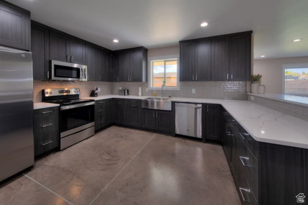 Kitchen featuring plenty of natural light, a sink, backsplash, and stainless steel appliances