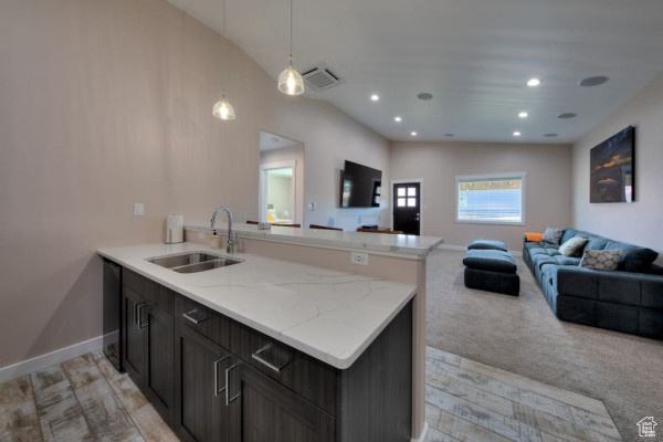 Kitchen featuring a peninsula, open floor plan, visible vents, and a sink