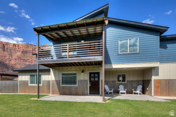Rear view of property featuring a patio, a yard, a balcony, and fence