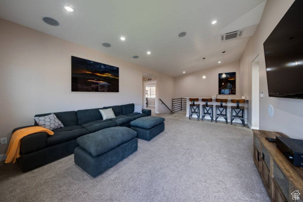 Carpeted living room with recessed lighting, vaulted ceiling, and visible vents