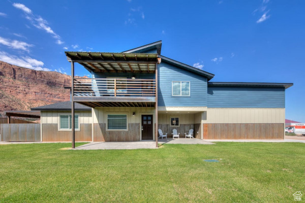 Back of property featuring a lawn, a patio, a mountain view, and a balcony