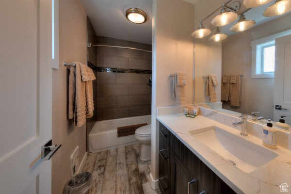 Full bath featuring bathtub / shower combination, vanity, toilet, wood finished floors, and visible vents