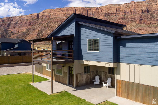 Rear view of property with a patio, a mountain view, and a yard