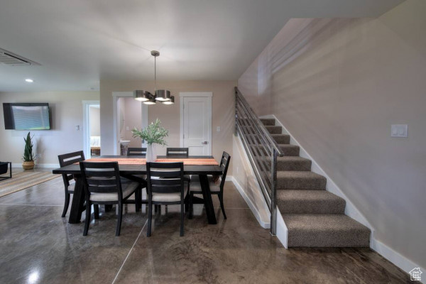 Dining room with baseboards, stairs, finished concrete flooring, and a chandelier