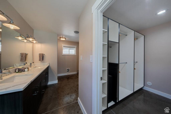 Full bath with a sink, baseboards, concrete floors, and double vanity