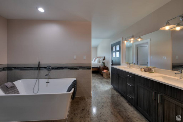 Full bathroom with double vanity, a freestanding bath, a sink, and ensuite bath