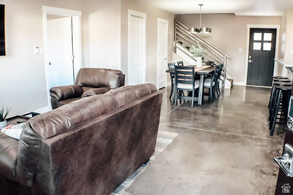 Living room featuring baseboards, concrete flooring, and stairs