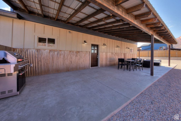 View of patio featuring outdoor dining area, fence, and a grill
