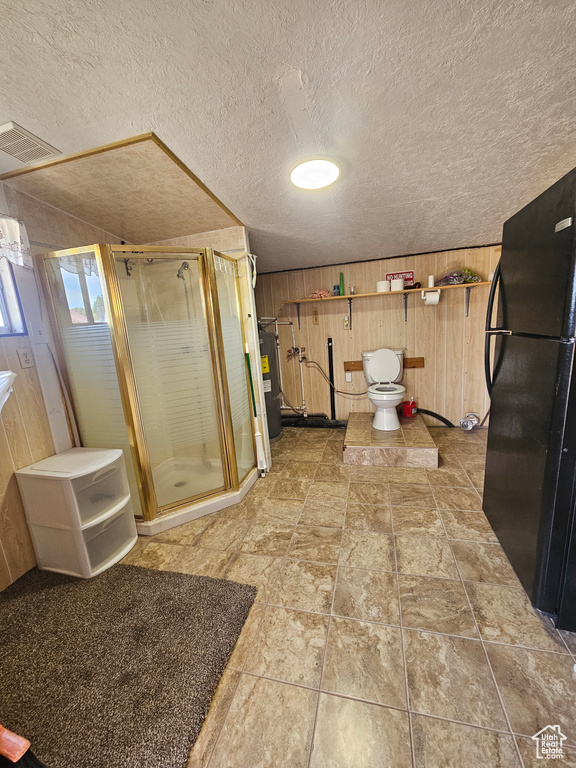 Bathroom with a shower stall, wooden walls, a textured ceiling, and water heater