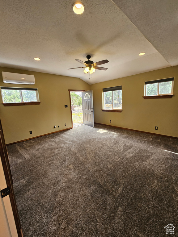 Spare room with a wall mounted air conditioner, baseboards, carpet, ceiling fan, and a textured ceiling