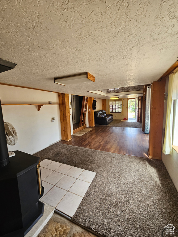 Carpeted living room with a wood stove, stairway, and a textured ceiling