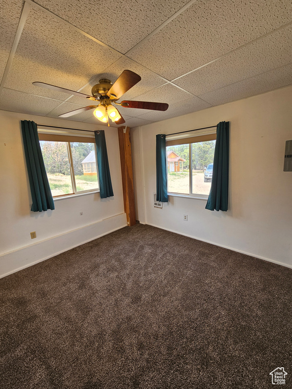 Spare room with dark colored carpet, ceiling fan, and baseboards