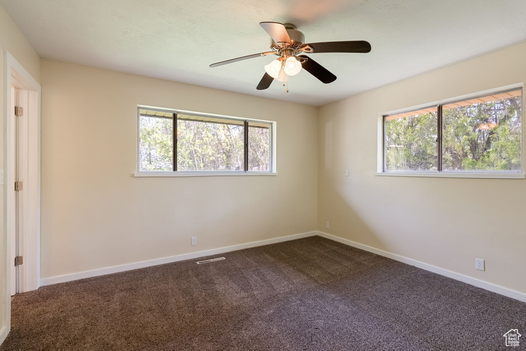 Unfurnished bedroom featuring dark colored carpet, baseboards, ceiling fan, and visible vents