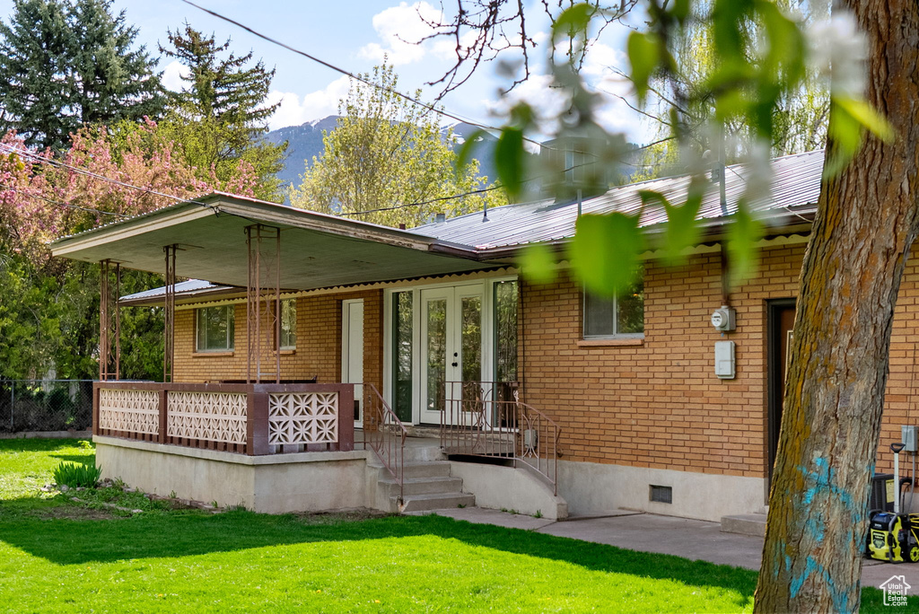 Rear view of house featuring brick siding, french doors, crawl space, a mountain view, and a lawn