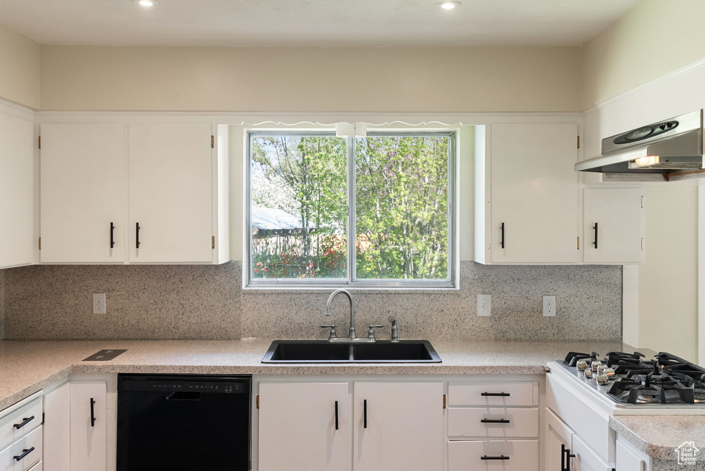 Kitchen with dishwasher, a sink, light countertops, under cabinet range hood, and white cabinetry