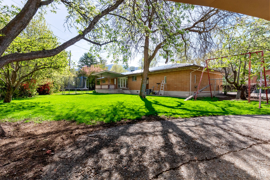 Back of property with a yard, brick siding, and a trampoline