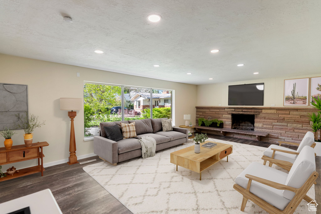 Living area featuring recessed lighting, baseboards, a stone fireplace, and wood finished floors