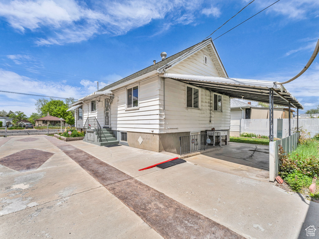 View of home\\\'s exterior featuring fence, a carport, and concrete driveway