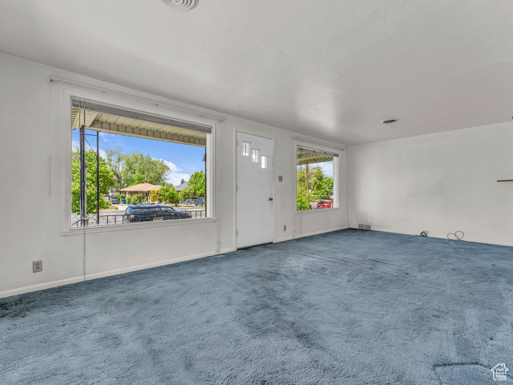 Unfurnished living room with baseboards, carpet, and visible vents
