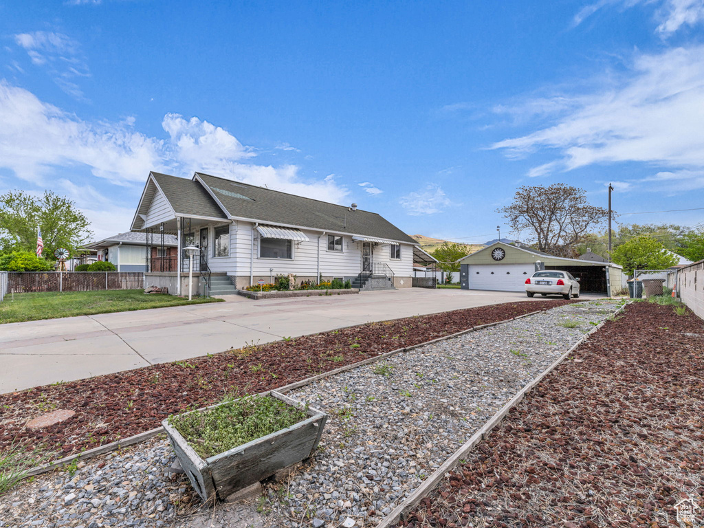 Ranch-style house with fence, an outdoor structure, a shingled roof, and concrete driveway