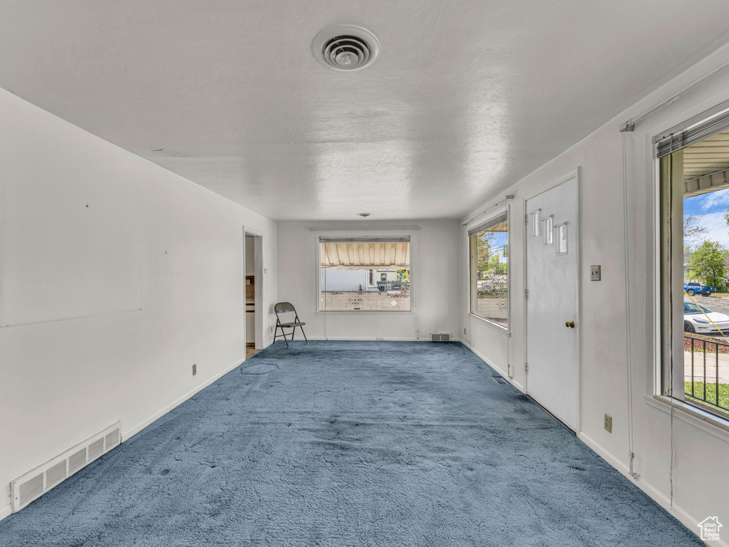 Unfurnished living room with a wealth of natural light, carpet flooring, and visible vents