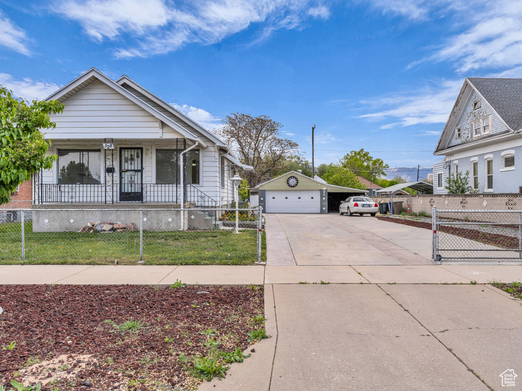 Bungalow-style home featuring a porch, a front yard, fence private yard, a garage, and an outdoor structure