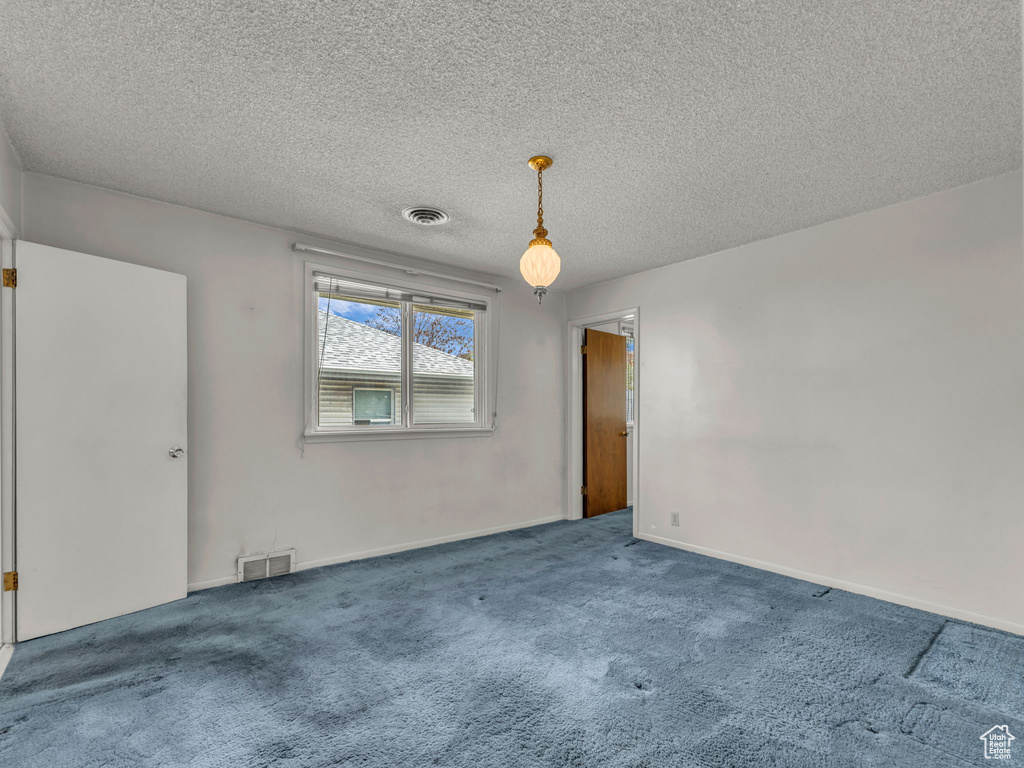 Unfurnished room featuring carpet floors, a textured ceiling, and visible vents