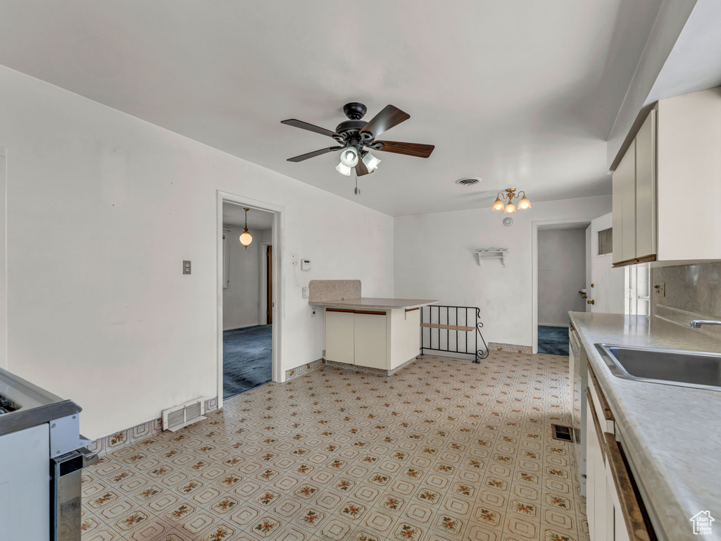 Kitchen with ceiling fan, a sink, baseboards, white cabinets, and a peninsula
