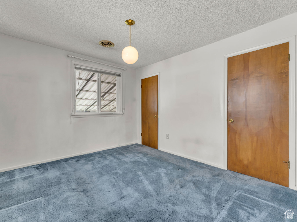Unfurnished bedroom with visible vents, a textured ceiling, carpet, and baseboards