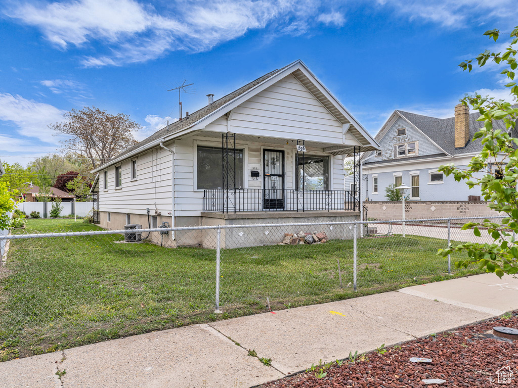 Bungalow-style home featuring a porch, a fenced front yard, and a front yard