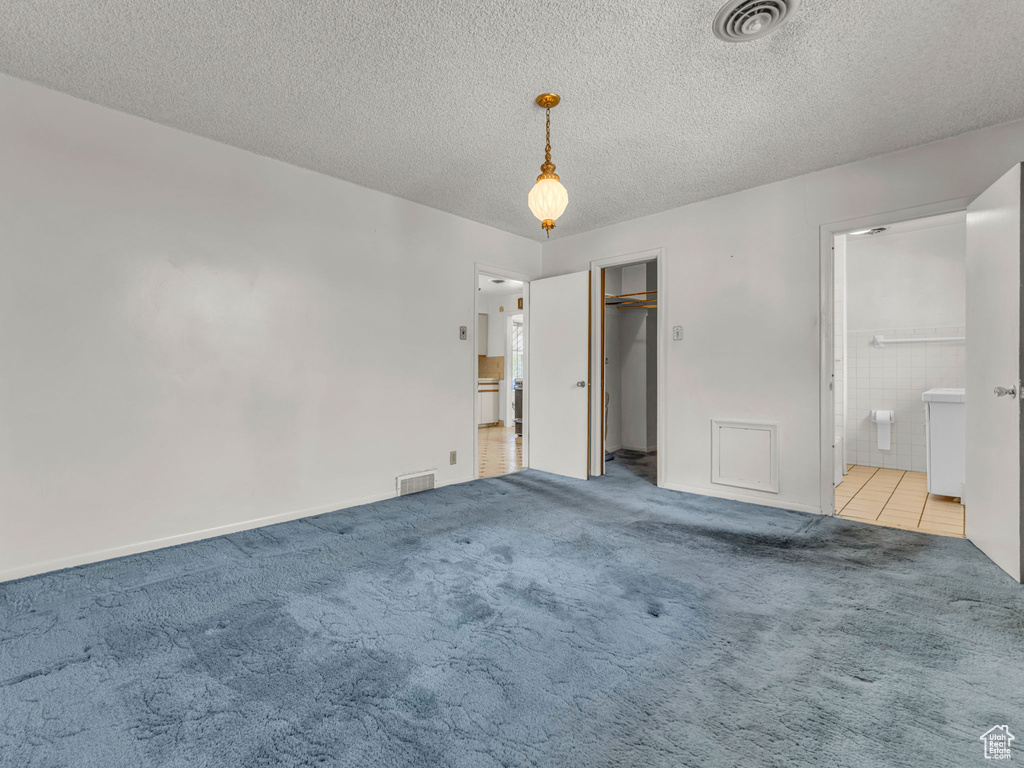 Unfurnished bedroom with light colored carpet, a textured ceiling, and visible vents