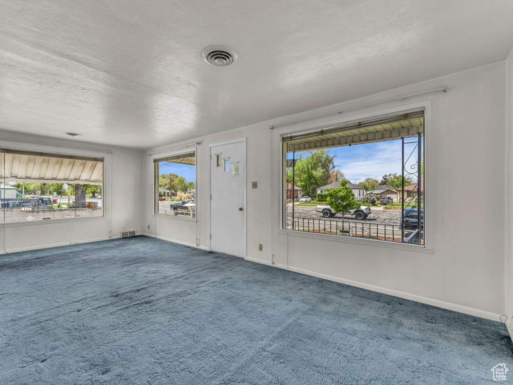 Interior space featuring a healthy amount of sunlight, baseboards, a textured ceiling, and visible vents
