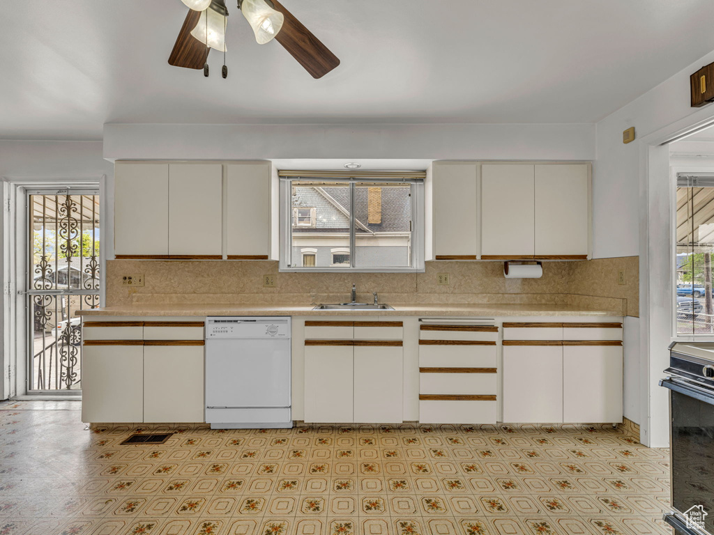 Kitchen with white dishwasher, ceiling fan, a sink, light countertops, and backsplash