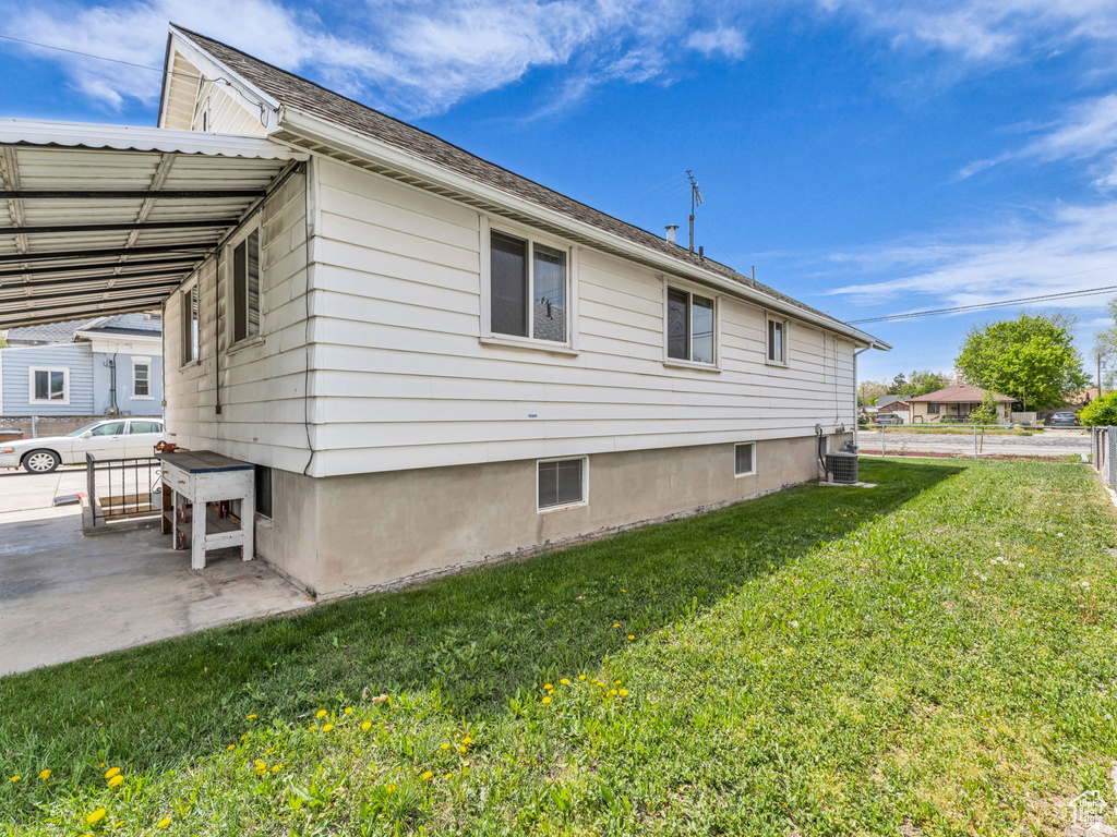 View of side of property featuring a lawn, a patio, central AC, and fence