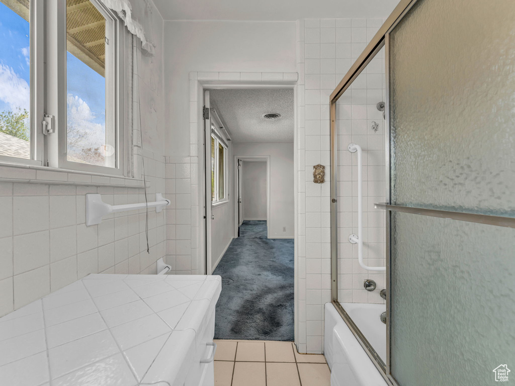 Bathroom with tile patterned floors and shower / bath combination with glass door