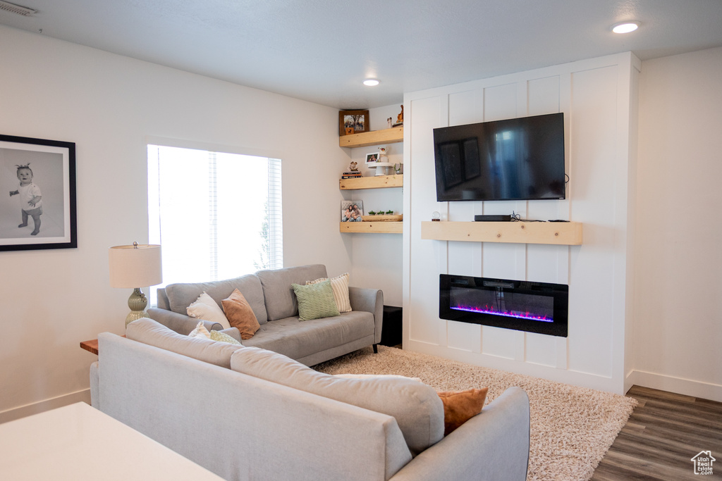Living area with dark wood-type flooring, recessed lighting, baseboards, and a glass covered fireplace