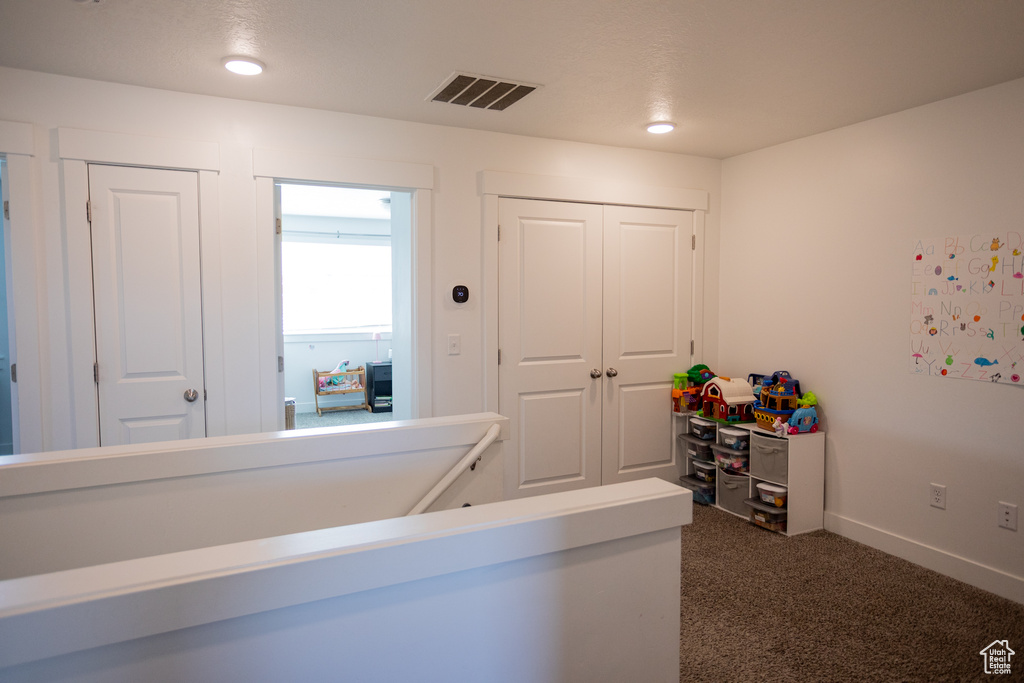 Hall with baseboards, dark colored carpet, and visible vents