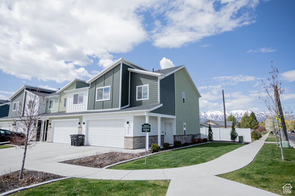 View of home's exterior with a lawn, fence, stone siding, concrete driveway, and an attached garage