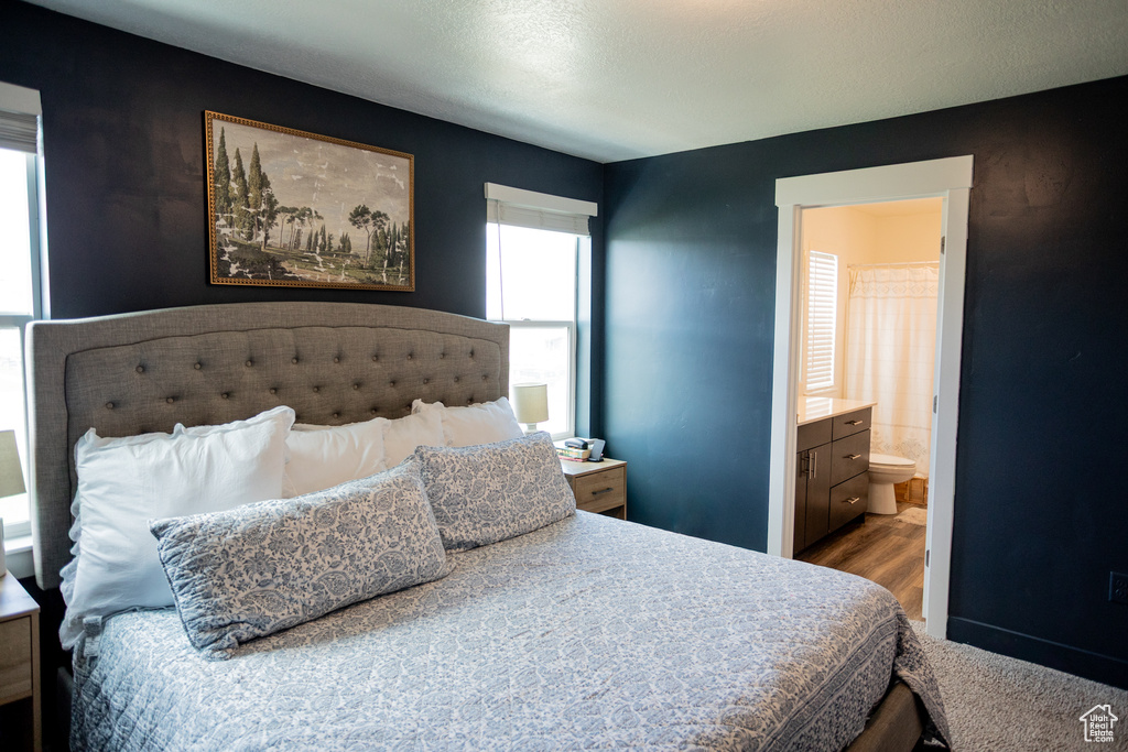 Bedroom with ensuite bathroom and wood finished floors