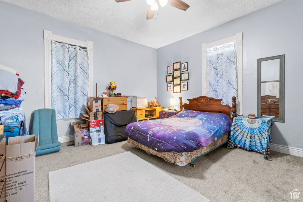 Bedroom featuring carpet, a textured ceiling, baseboards, and ceiling fan