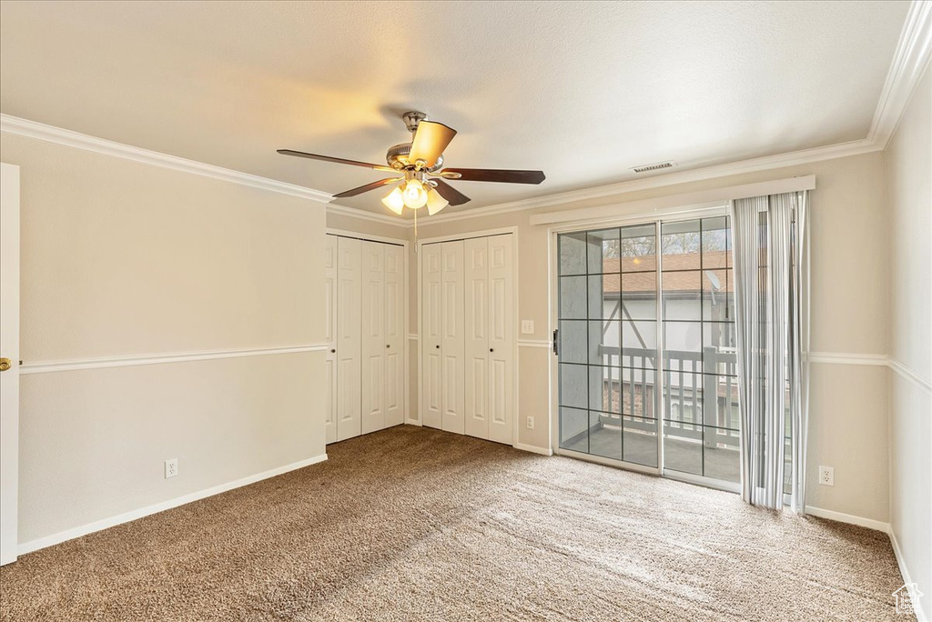 Unfurnished room featuring carpet flooring, ceiling fan, visible vents, and crown molding