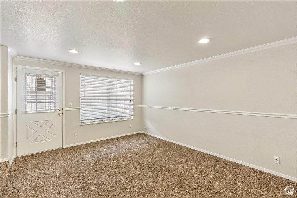 Carpeted spare room featuring crown molding, baseboards, and recessed lighting